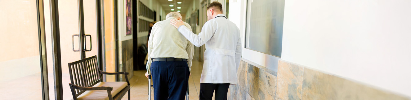 Doctor and retired mature man taking a walk at the retirement home